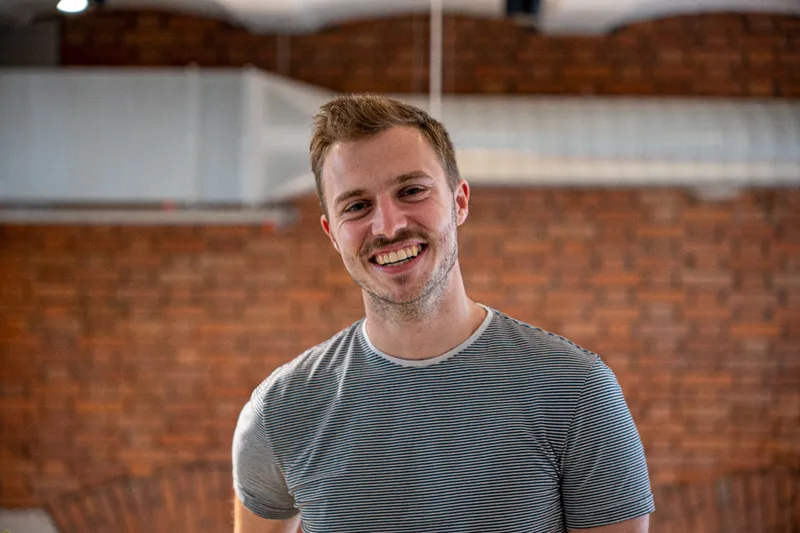 Samuel Biederbeck lächelnd vor einer Klinkerfassade